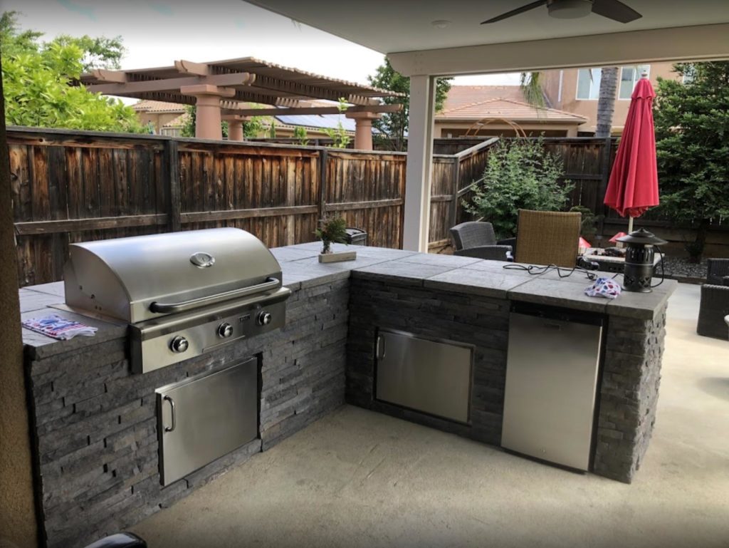Custom outdoor kitchen and patio in backyard.